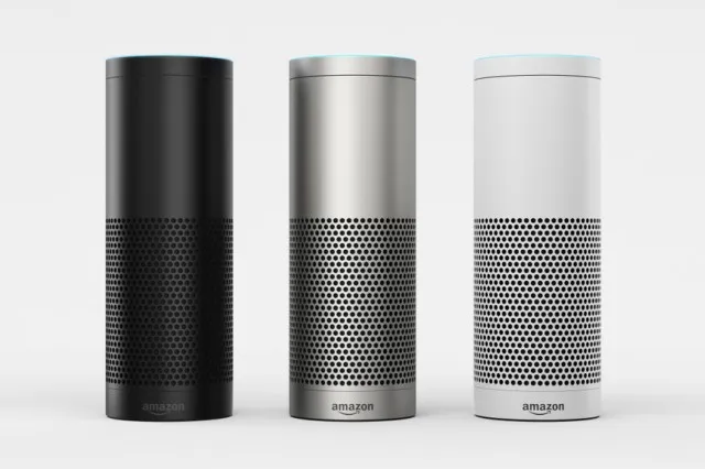 A cylindrical Amazon Echo speaker on a surface with a person nearby speaking toward it