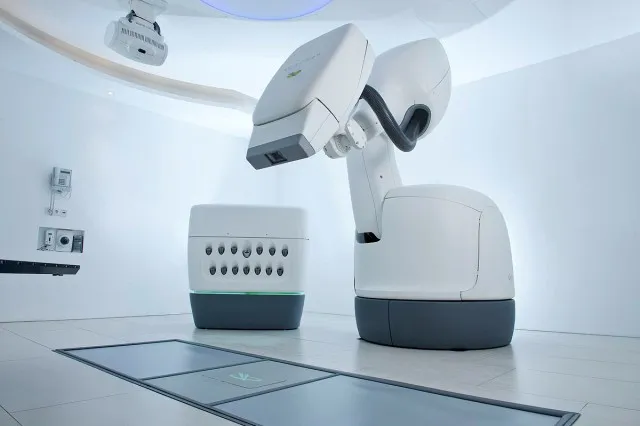 Robotic arm mounted on a ring-shaped gantry positioned around a treatment table