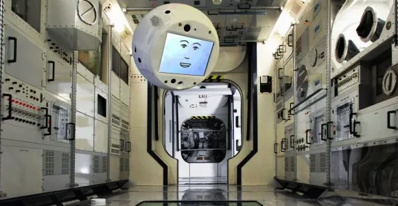 A white spherical floating robot with a screen face displaying eyes, inside the International Space Station