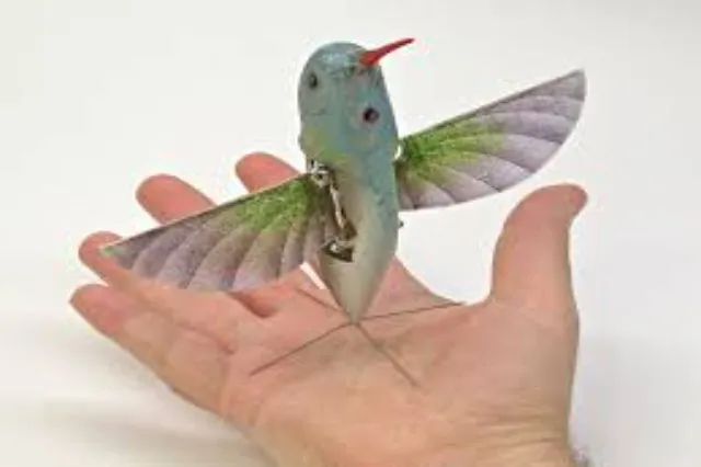 A small robotic aircraft shaped like a hummingbird, with narrow wings and a camera payload