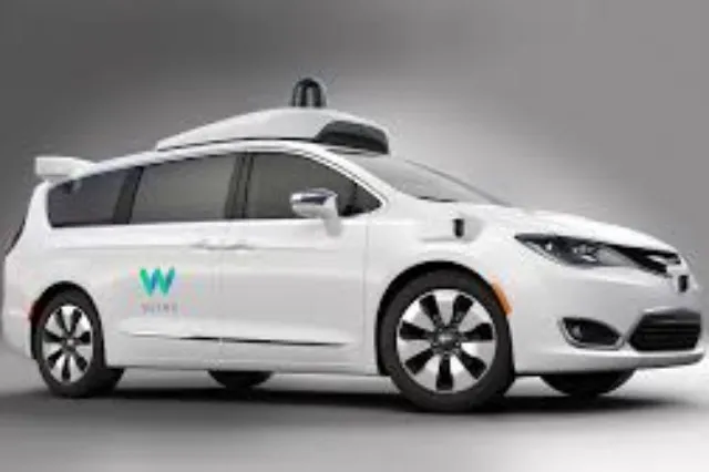A white autonomous vehicle with sensor arrays on the roof, on a road in a suburban area