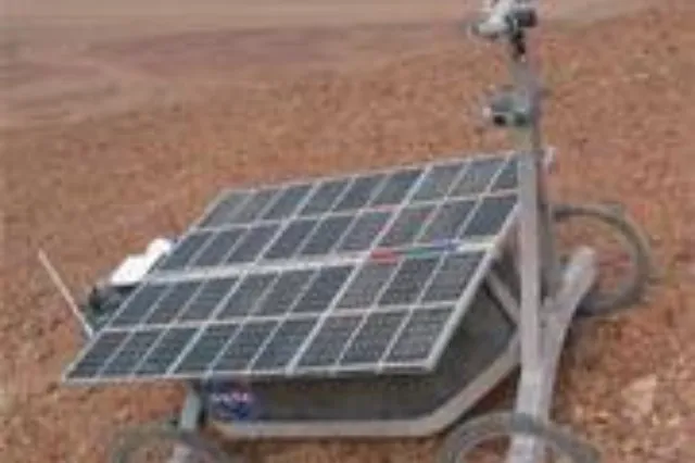 A four-wheeled rover on a dry, rocky desert landscape under an open sky
